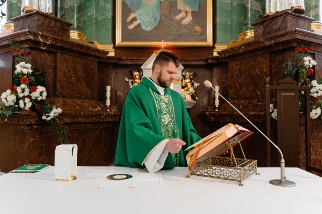 Ksiądz w zielonej stule czyta z księgi liturgicznej przy ołtarzu