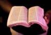 Naucz się kochać jak Jezus: 7 ewangelicznych kroków na dziś Otwarta Biblia trzymana w dłoniach w dramatycznym świetle