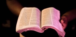Naucz się kochać jak Jezus: 7 ewangelicznych kroków na dziś Otwarta Biblia trzymana w dłoniach w dramatycznym świetle
