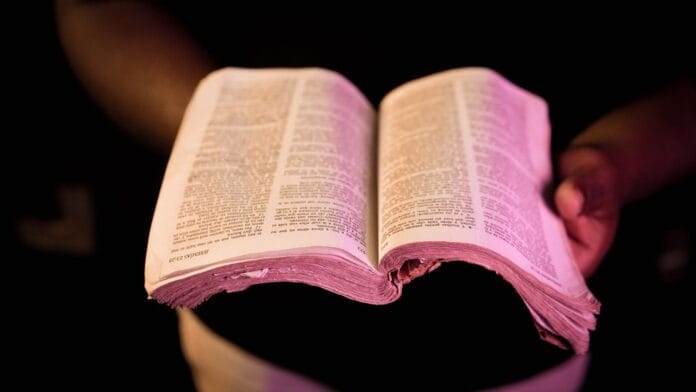 Otwarta Biblia trzymana w dłoniach w dramatycznym świetle