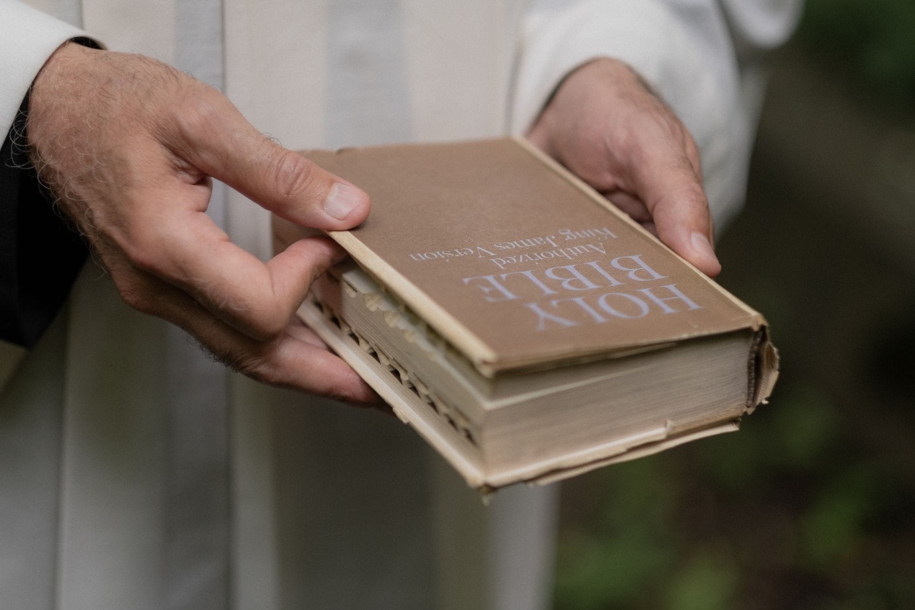 Starsza osoba trzyma w dłoniach zużytą Biblię