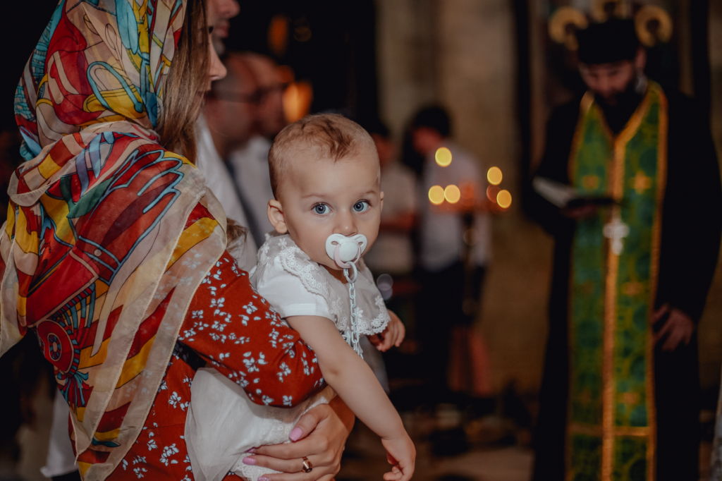 Matka trzymająca niemowlę podczas ceremonii w cerkwi prawosławnej