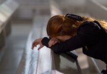Święta Monika – jak nie tracić nadziei i modlić się o nawrócenie zbuntowanego dziecka? Rudowłosa kobieta modląca się przy ławce w kościele