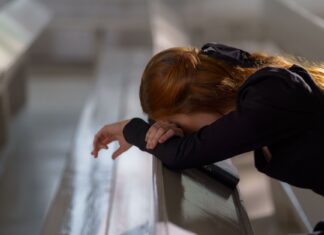 Święta Monika – jak nie tracić nadziei i modlić się o nawrócenie zbuntowanego dziecka? Rudowłosa kobieta modląca się przy ławce w kościele